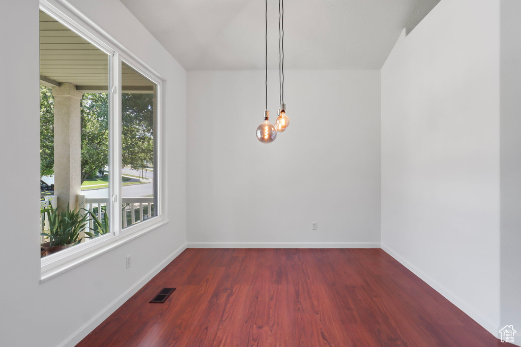 Unfurnished dining area with healthy amount of natural light, wood finished floors, and a chandelier