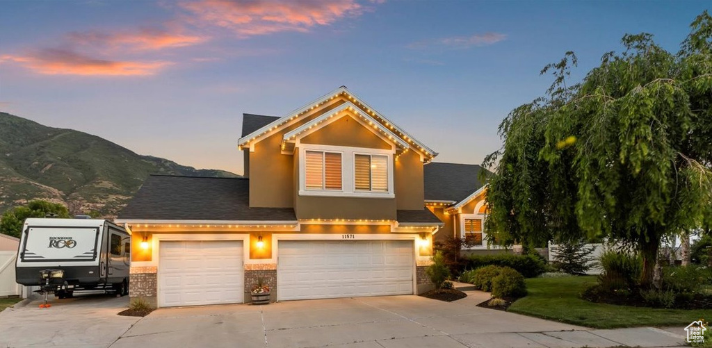 View of front of house with concrete driveway, stucco siding, a garage, and a mountain view