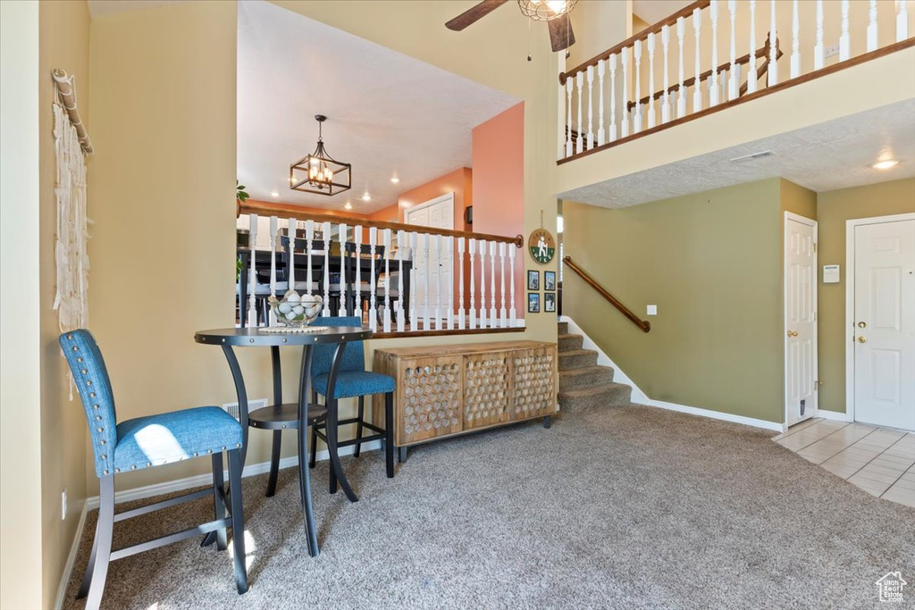 Dining space with carpet flooring, stairway, a chandelier, and a ceiling fan