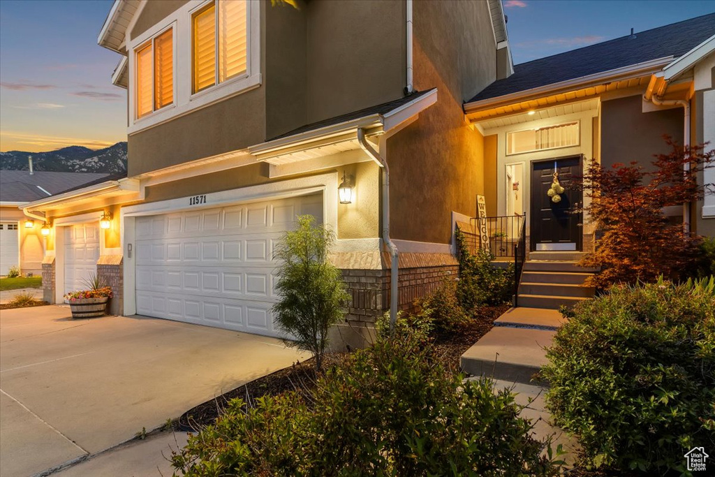 View of front of home with an attached garage, driveway, and stucco siding
