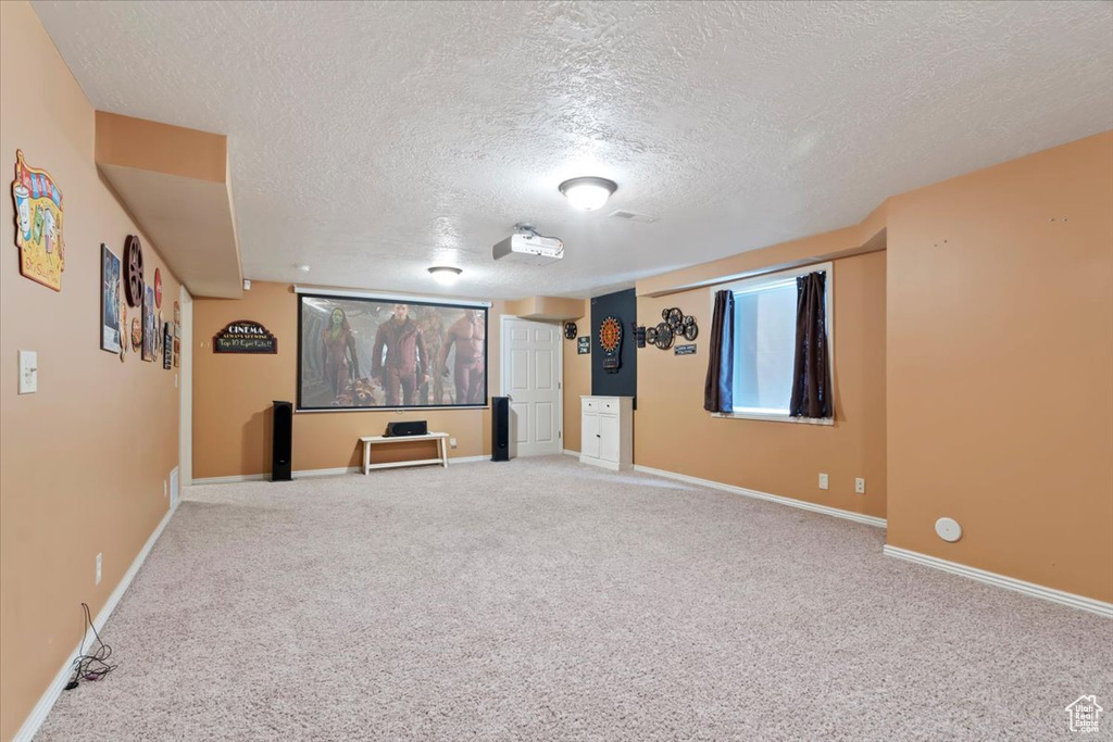 Carpeted cinema featuring a textured ceiling and baseboards