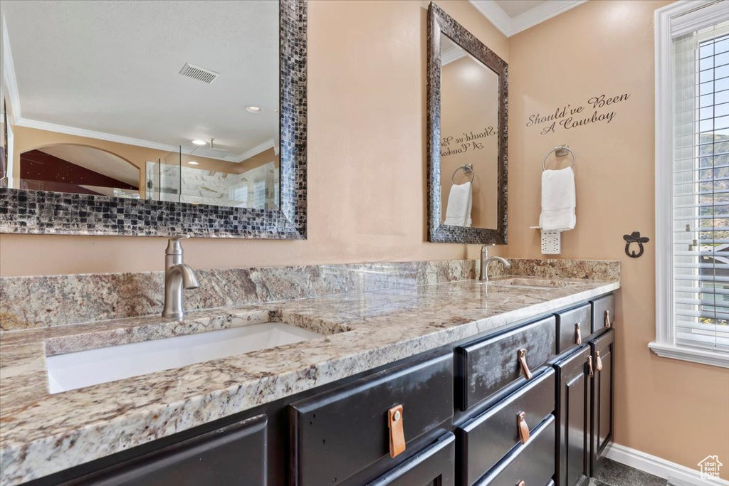 Bathroom with ornamental molding, double vanity, and a shower