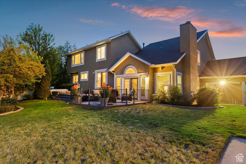 Rear view of property featuring a chimney, stucco siding, a yard, and french doors