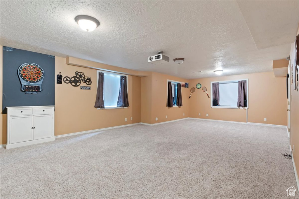 Carpeted spare room with a textured ceiling and baseboards