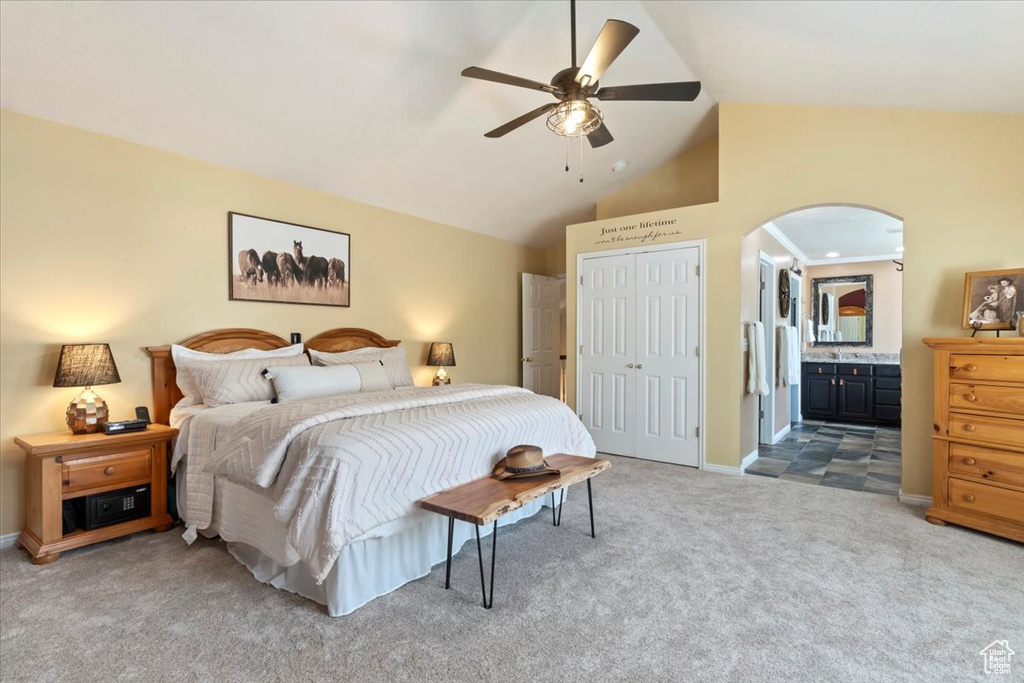Bedroom featuring carpet flooring, lofted ceiling, a closet, arched walkways, and ensuite bath