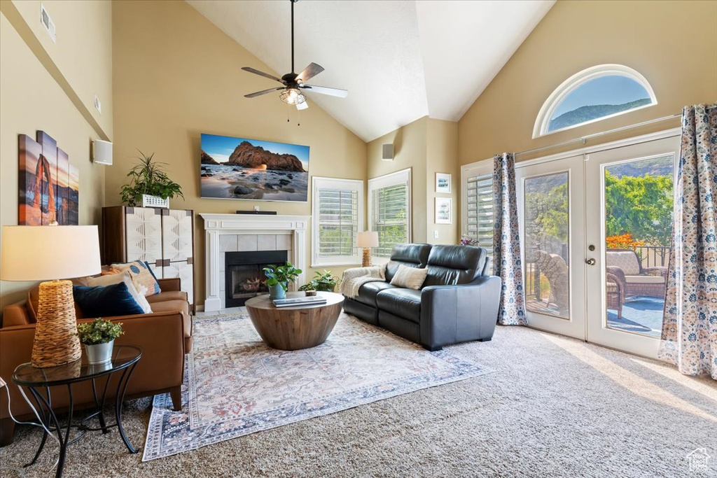 Carpeted living area featuring high vaulted ceiling, a ceiling fan, french doors, and a tile fireplace