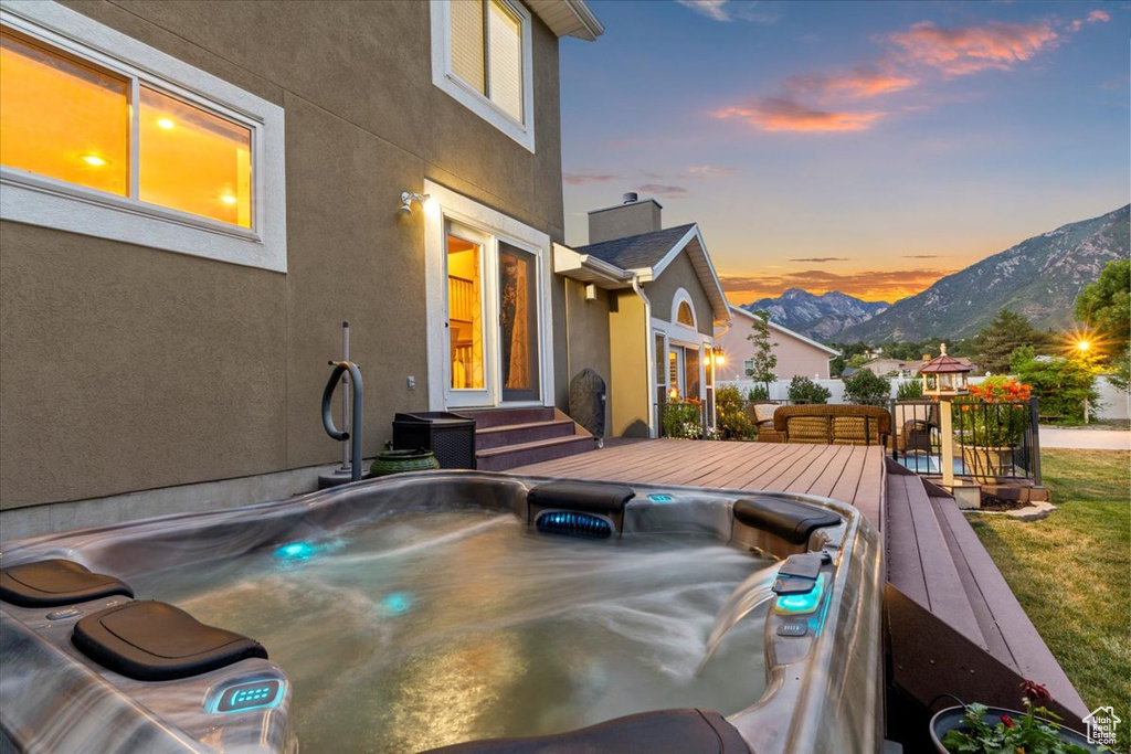 Deck at dusk with a hot tub and a mountain view