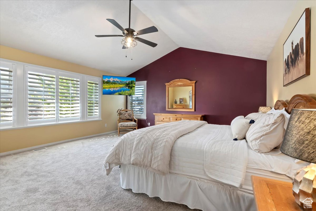 Carpeted bedroom featuring vaulted ceiling and a ceiling fan