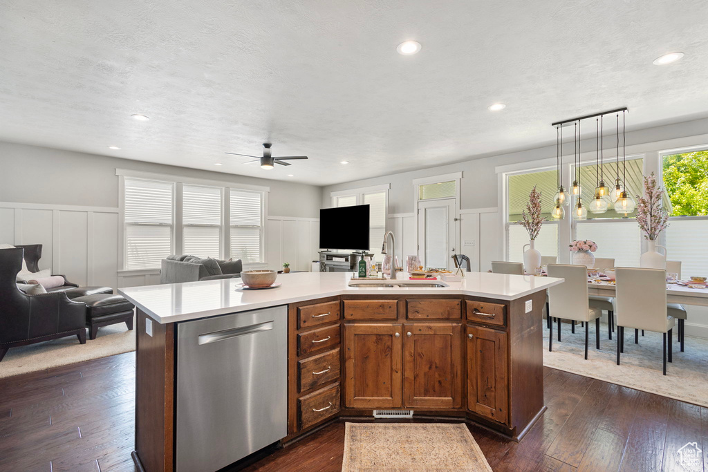 Kitchen with stainless steel dishwasher, open floor plan, a decorative wall, ceiling fan, and light countertops