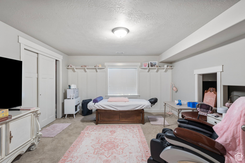 Bedroom featuring light carpet, a textured ceiling, and a closet