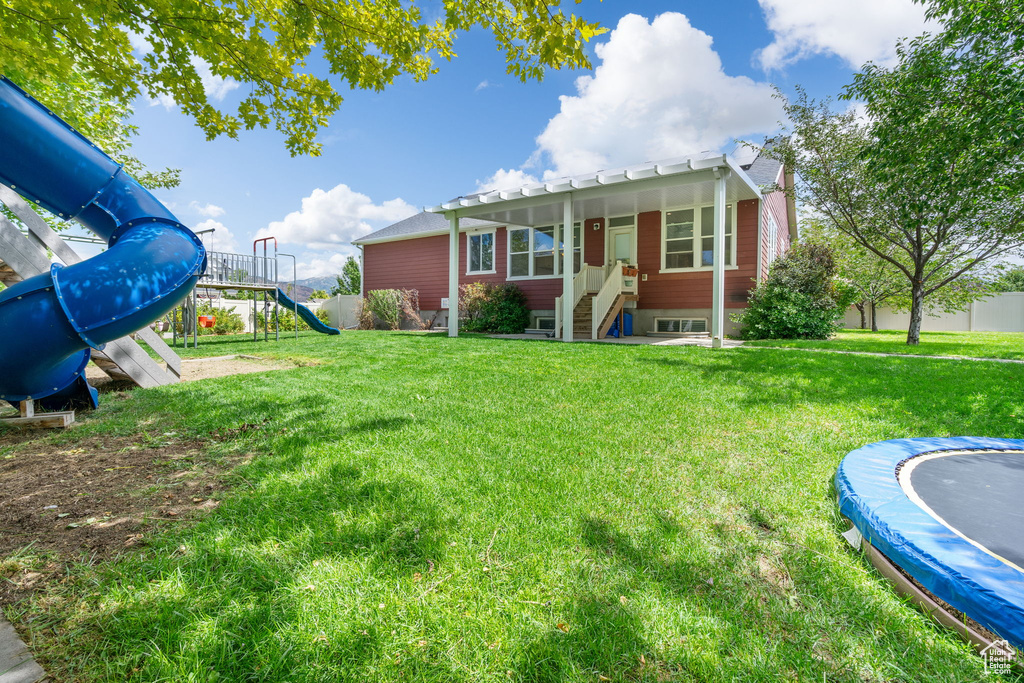 View of yard featuring a playground and a trampoline