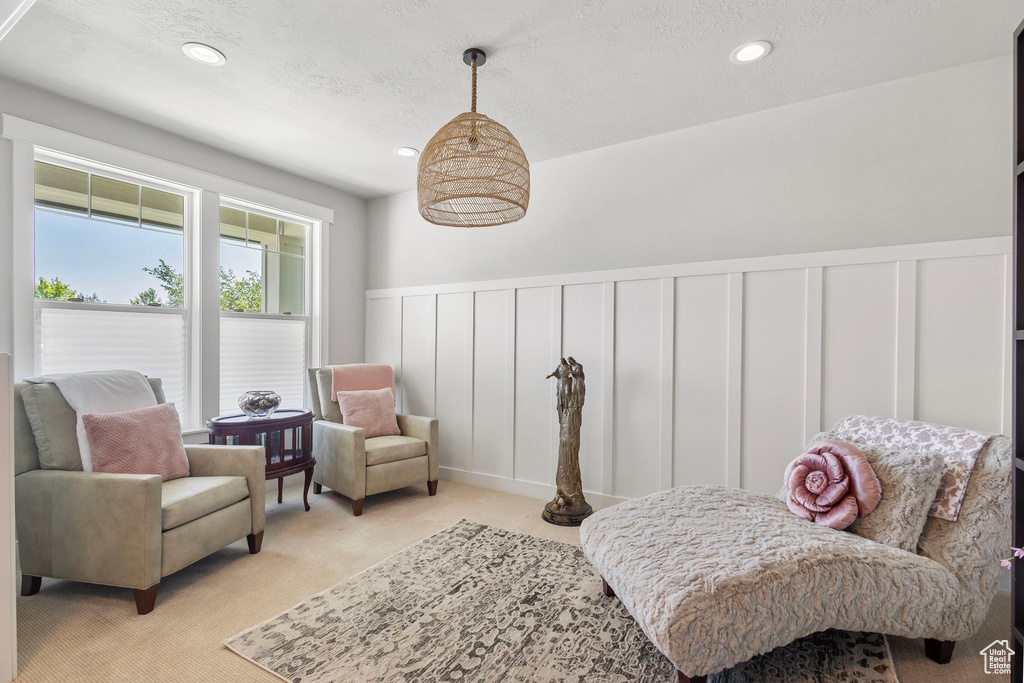 Sitting room featuring a decorative wall, wainscoting, light carpet, recessed lighting, and a textured ceiling