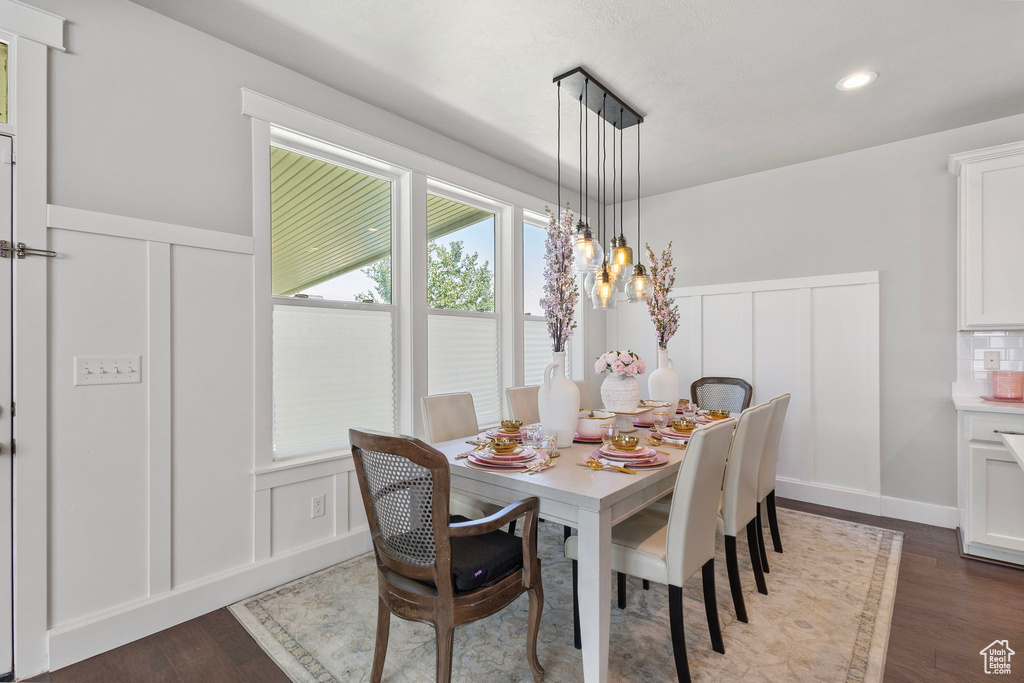 Dining area with a decorative wall, dark wood-style floors, a wainscoted wall, recessed lighting, and a chandelier