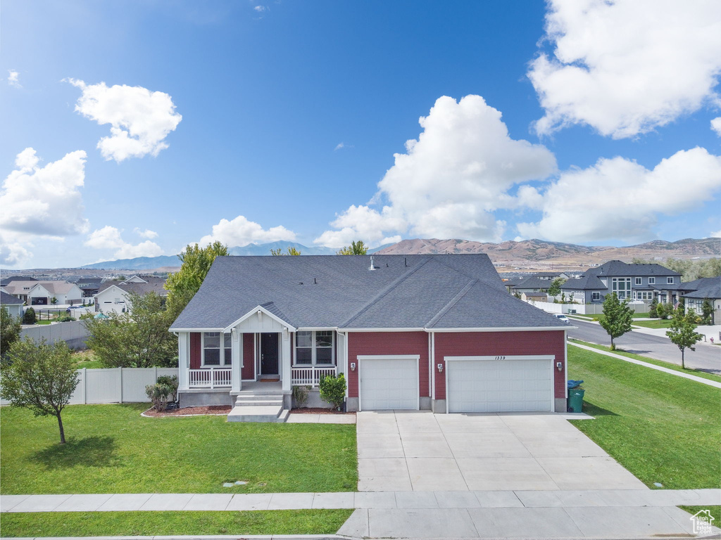 View of front of home with a garage, covered porch, a mountain view, driveway, and roof with shingles