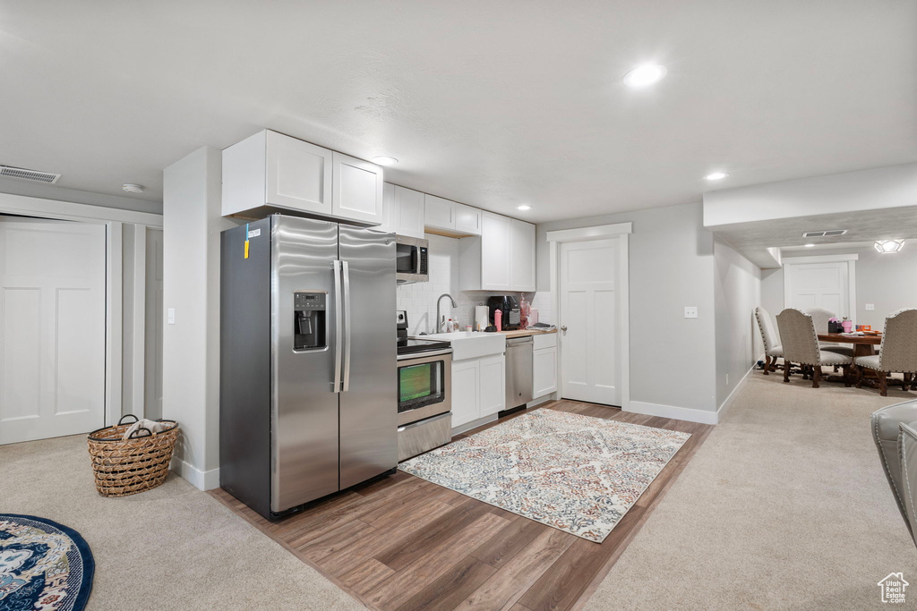 Kitchen featuring appliances with stainless steel finishes, white cabinets, backsplash, recessed lighting, and light wood finished floors