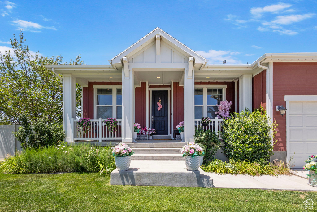 View of front of home with covered porch, board and batten siding, a garage, and a front yard