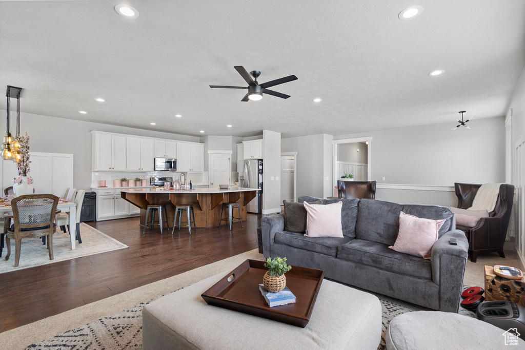 Living room featuring dark wood-style floors, a ceiling fan, recessed lighting, and a chandelier
