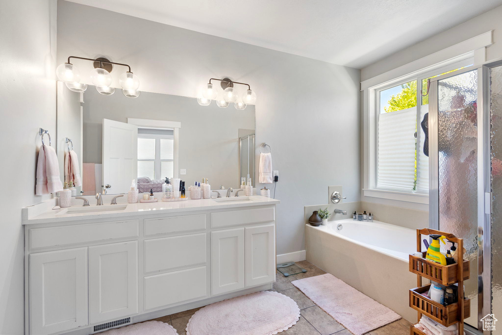 Bathroom featuring a garden tub, double vanity, tile patterned floors, and a shower