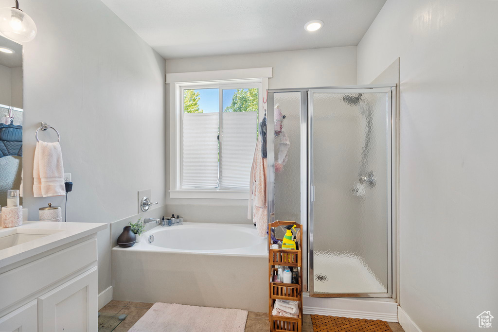 Full bathroom featuring a shower stall, a garden tub, vanity, and tile patterned flooring