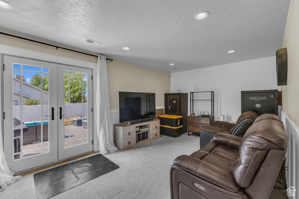 Carpeted living room featuring french doors, recessed lighting, and a textured ceiling