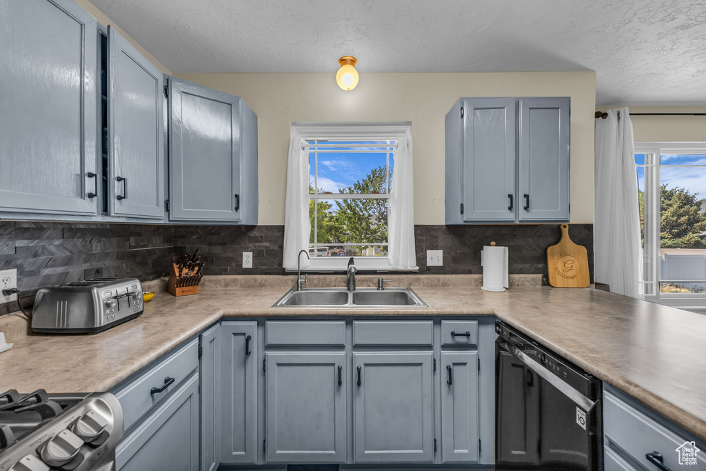 Kitchen featuring dishwasher, plenty of natural light, a textured ceiling, stainless steel gas range, and decorative backsplash