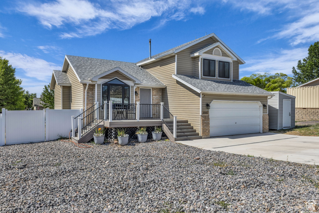 View of front of house with driveway, a shingled roof, and an attached garage