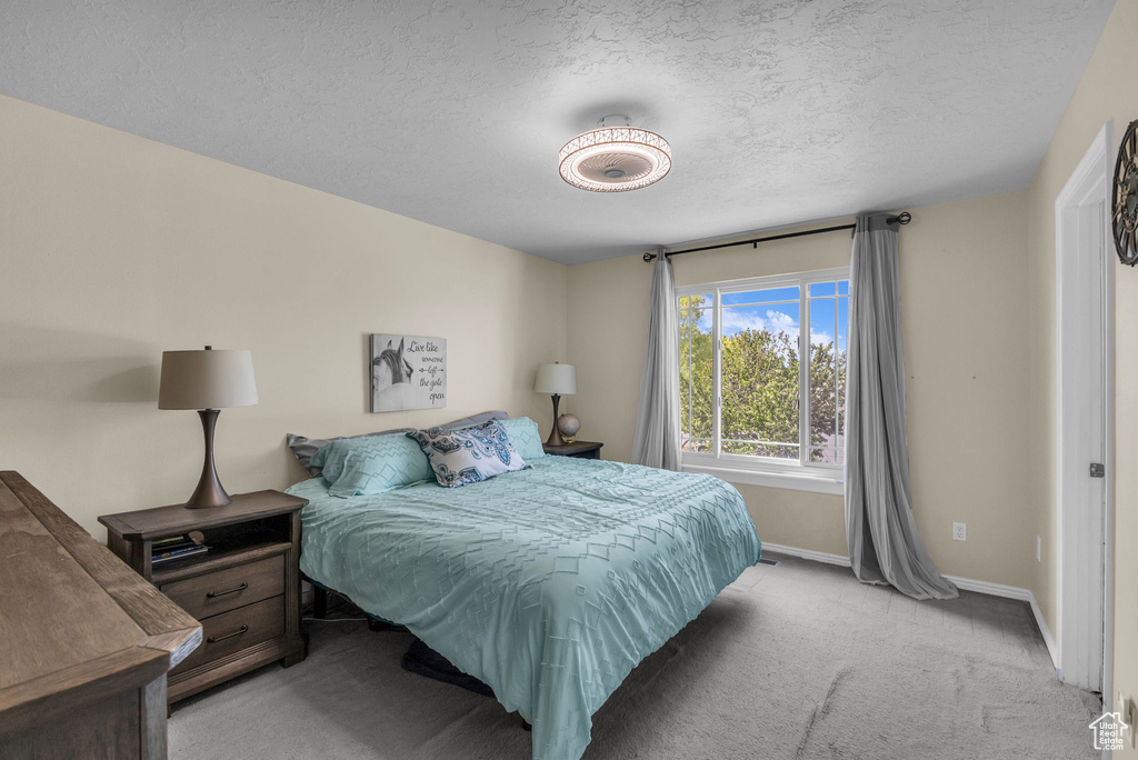 Bedroom with light colored carpet and a textured ceiling