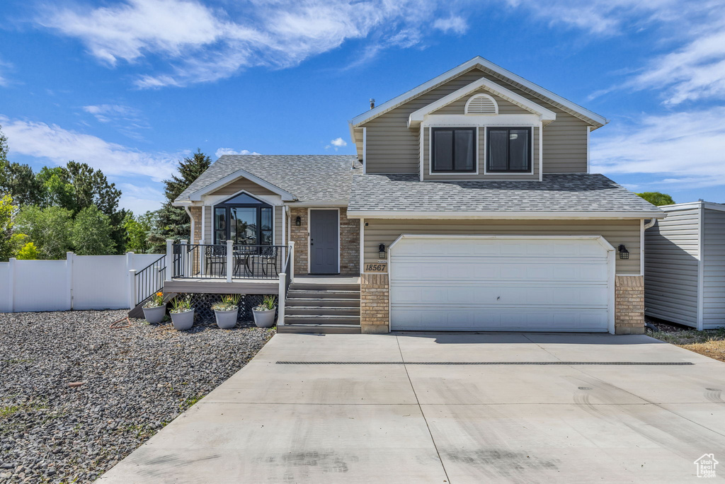 View of front of home with a garage, a shingled roof, concrete driveway, and a porch