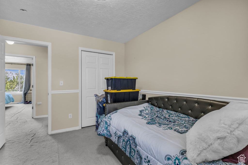 Bedroom featuring carpet, a textured ceiling, and a closet