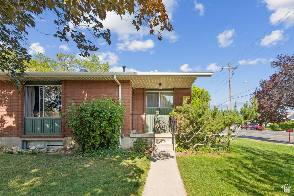 View of front of property with a front yard, brick siding, and a porch