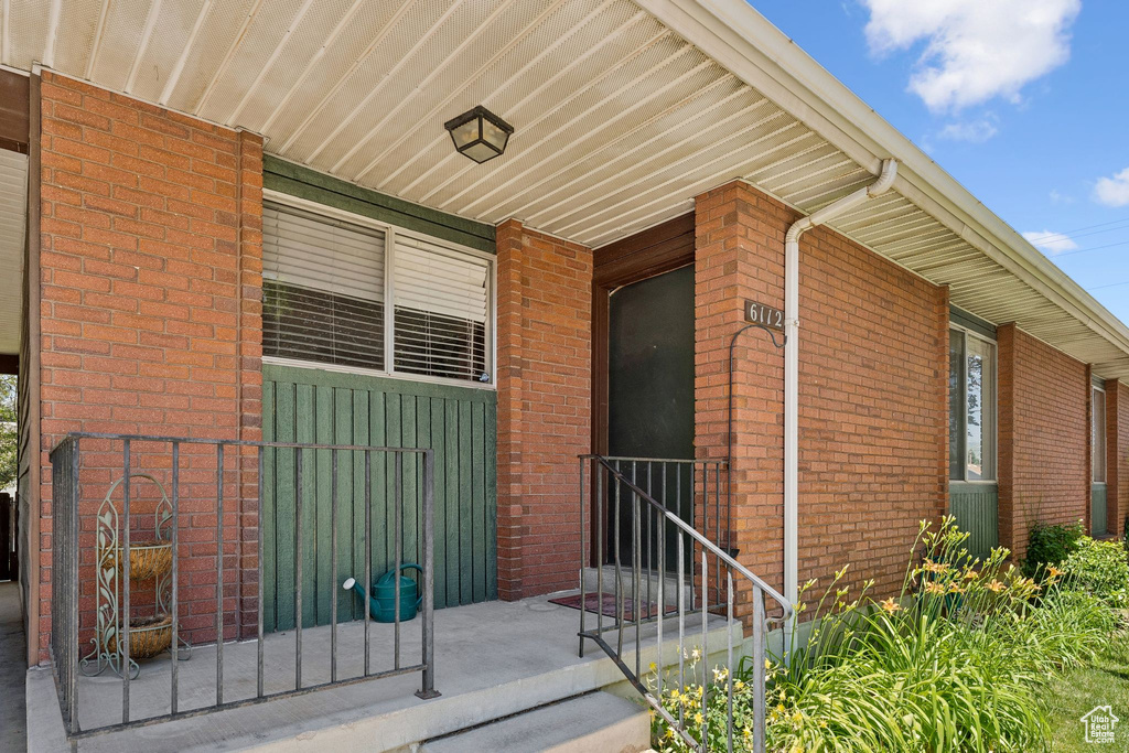 Doorway to property featuring brick siding and a porch