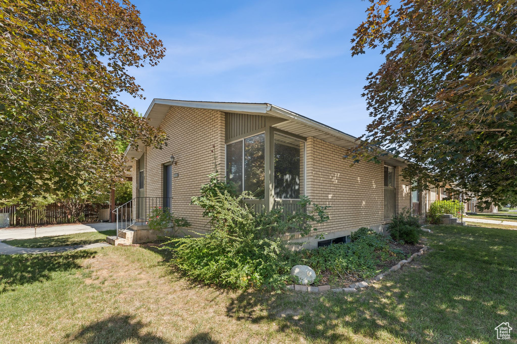 View of side of home featuring brick siding and a lawn