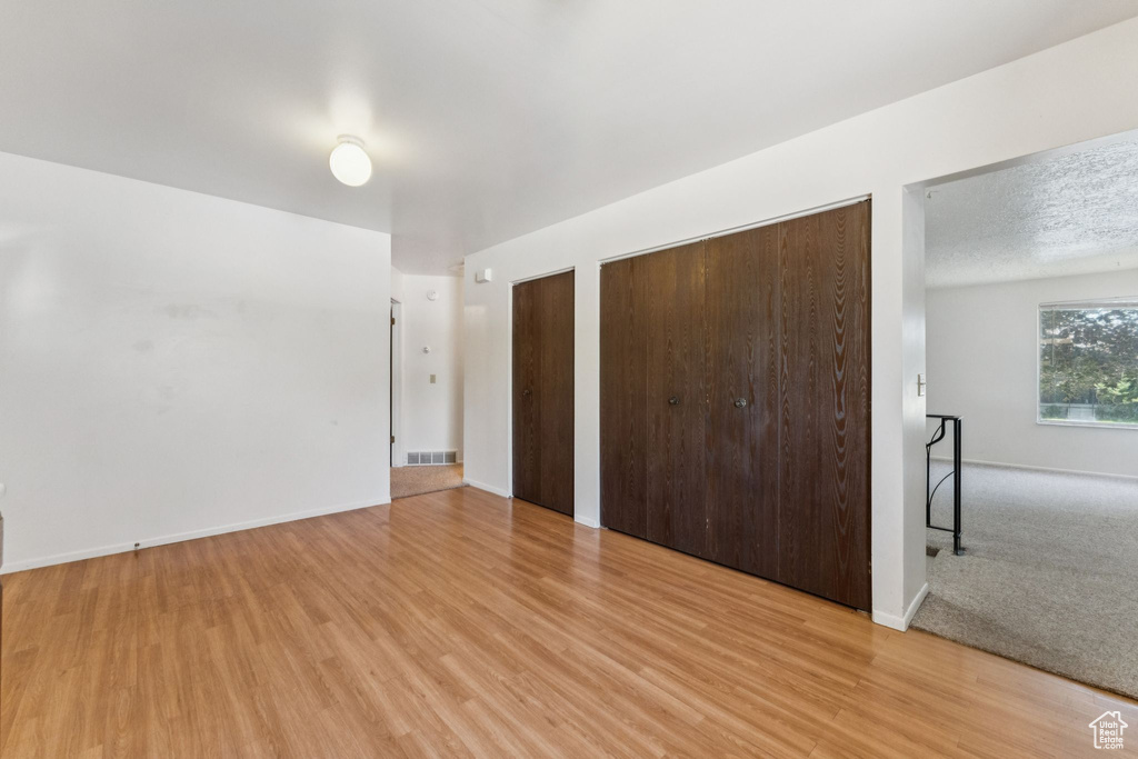 Unfurnished bedroom with light wood-style floors and two closets