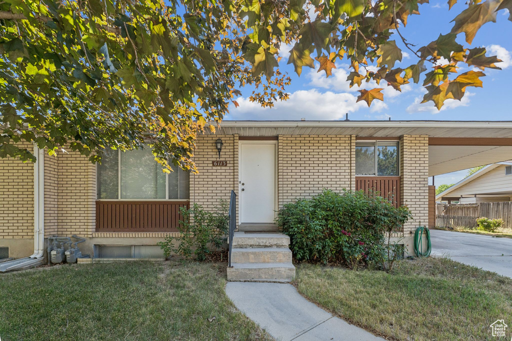 Property entrance with brick siding, an attached carport, and driveway
