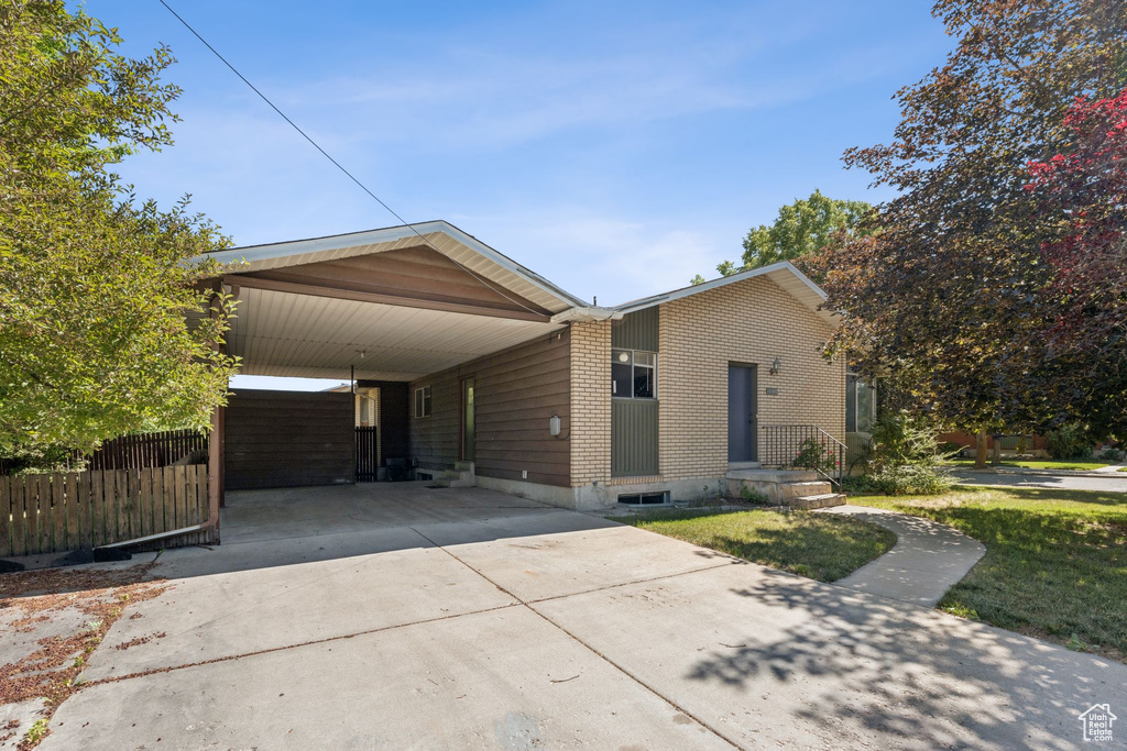 View of front of house featuring concrete driveway, brick siding, and an attached carport