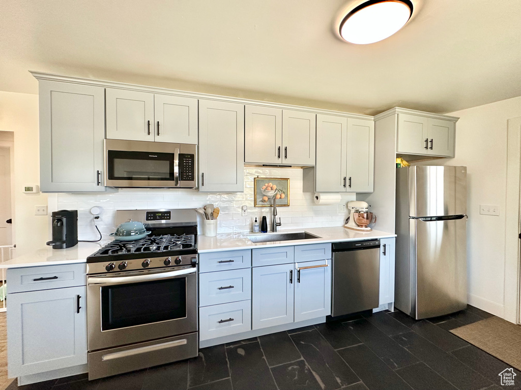 Kitchen featuring stainless steel appliances, light countertops, and backsplash