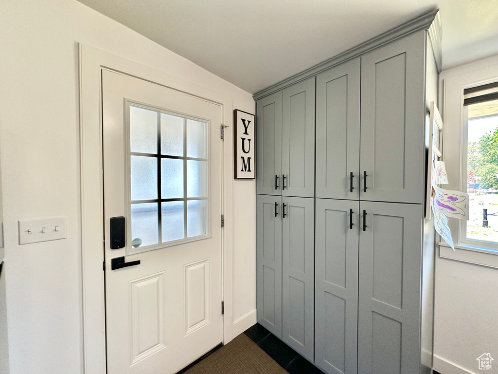 Doorway to outside featuring baseboards and dark tile patterned flooring