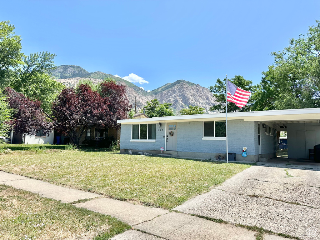 View of front of house with a mountain view, a front yard, a carport, driveway, and brick siding