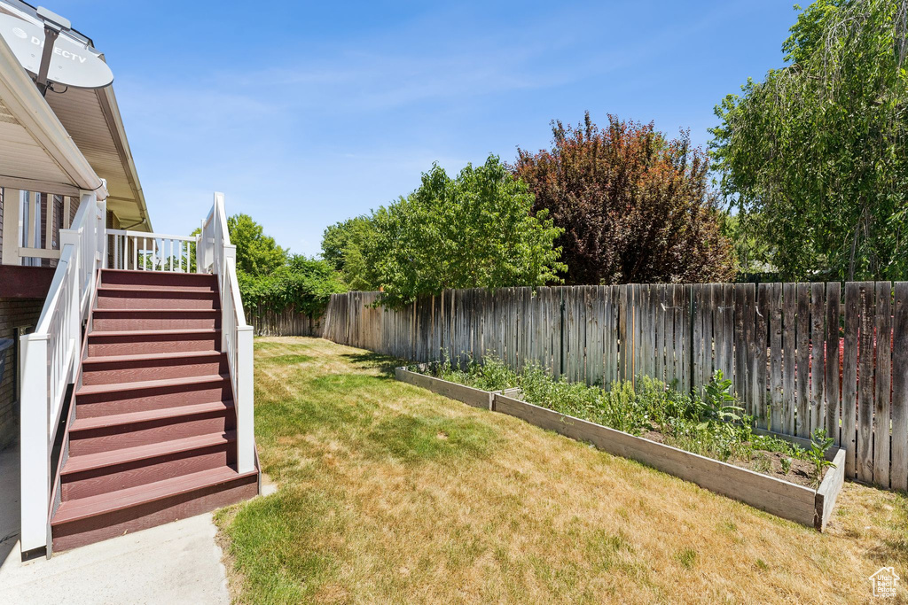 Fenced backyard with a vegetable garden, stairs, and a wooden deck