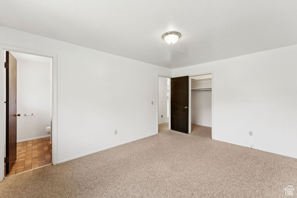 Unfurnished bedroom with light carpet, a closet, and ensuite bath