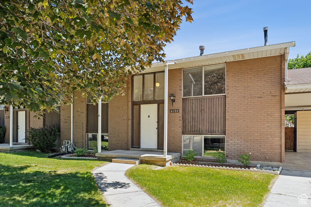 View of front of property featuring a front lawn and brick siding