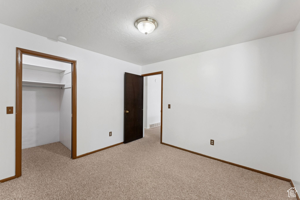 Unfurnished bedroom with light colored carpet and a closet