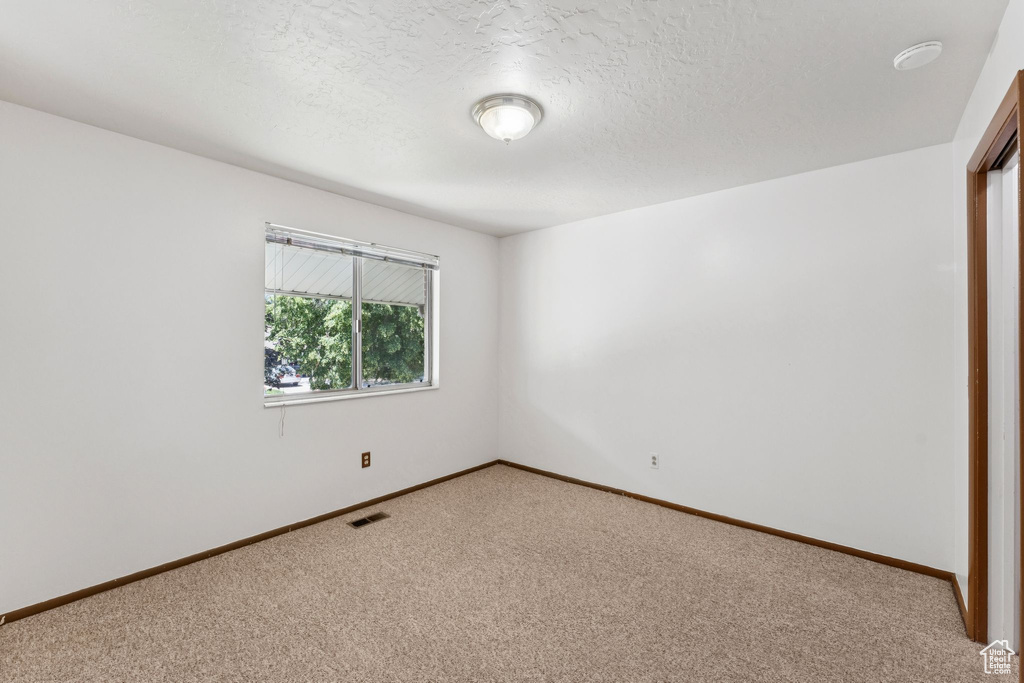 Spare room featuring light carpet and a textured ceiling