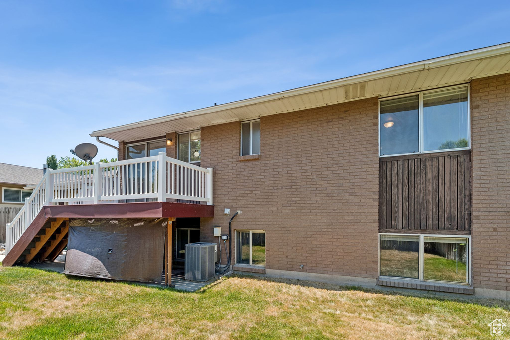 Rear view of property with a wooden deck, a yard, stairs, and brick siding