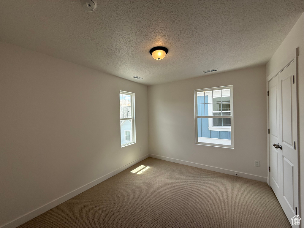 Unfurnished room with light carpet and a textured ceiling