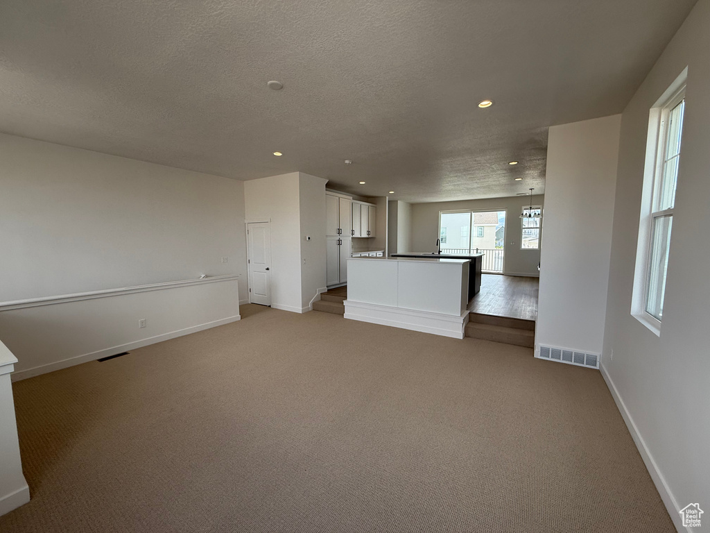 Unfurnished living room featuring recessed lighting, light colored carpet, and a textured ceiling