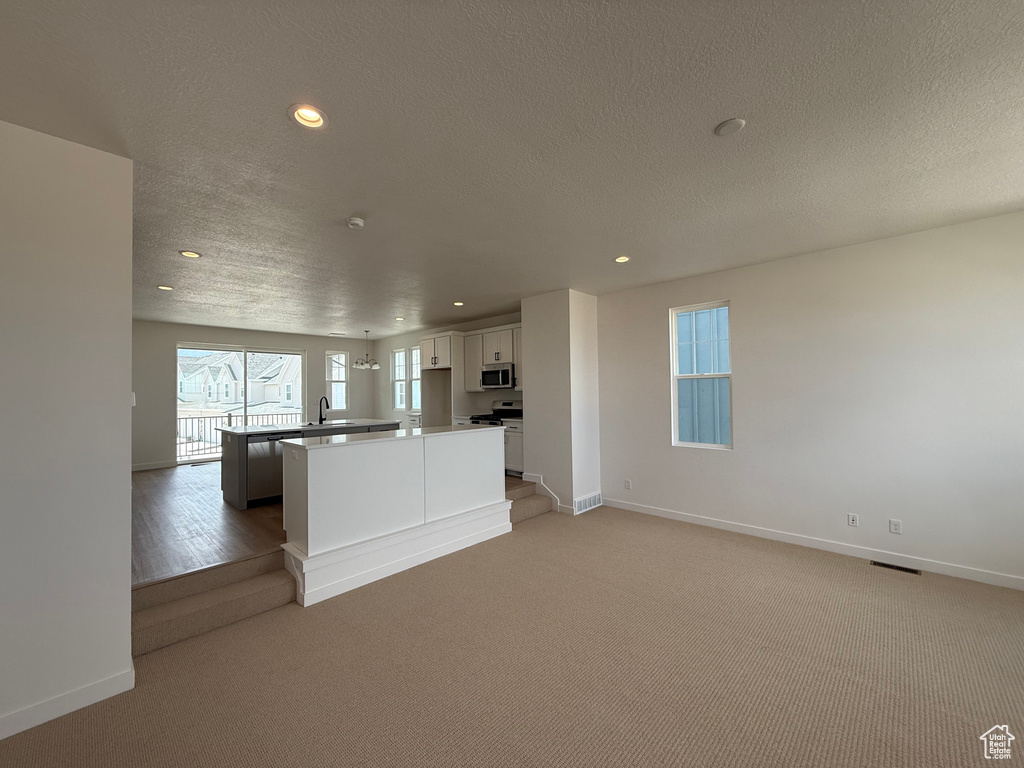 Kitchen with stainless steel microwave, recessed lighting, gas stove, a kitchen island, and white cabinetry