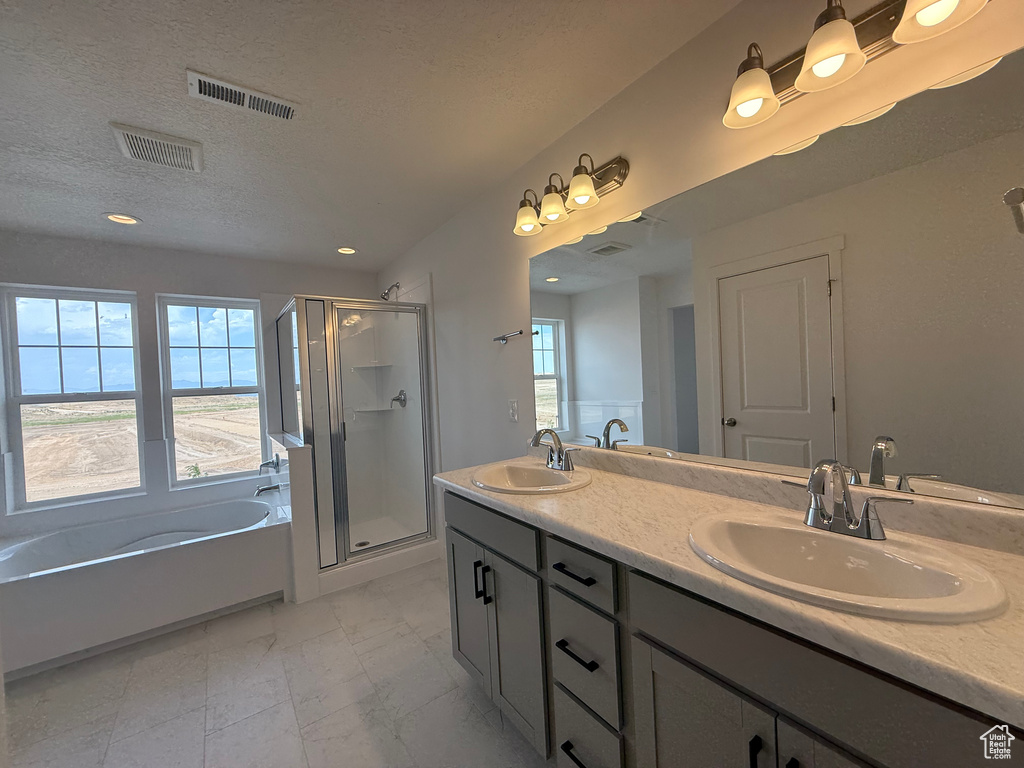 Full bath featuring a garden tub, a shower stall, double vanity, marble look tile flooring, and a textured ceiling