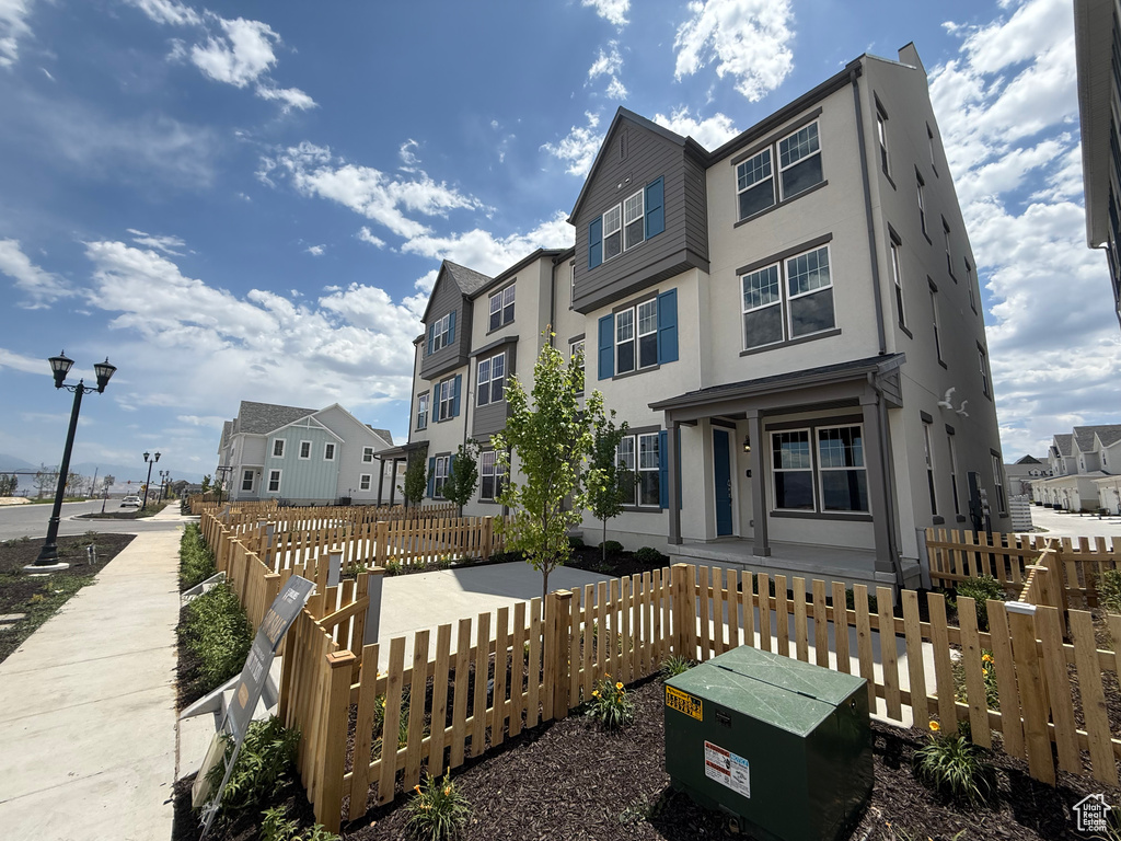 View of front of home featuring stucco siding, a fenced front yard, and a residential view