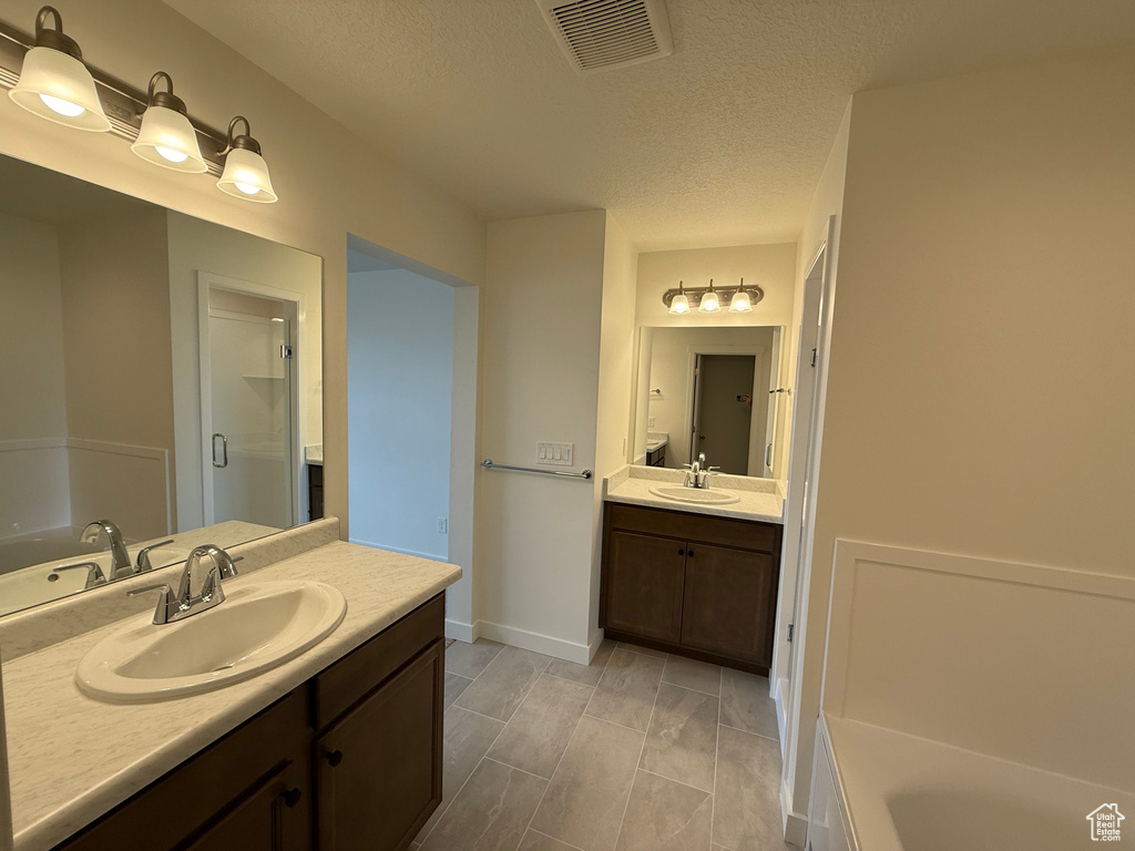 Full bath with vanity, a garden tub, a stall shower, and a textured ceiling